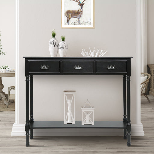 A black console table with three drawers, placed against a blue wall with a lamp and decorative items on top.