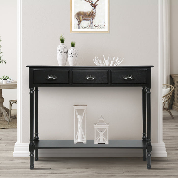 A black console table with three drawers, placed against a blue wall with a lamp and decorative items on top.